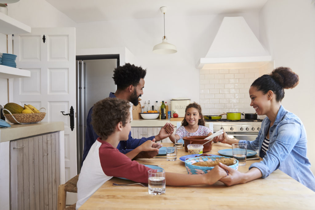 family-hold-hands-around-the-kitchen-table-before-their-meal